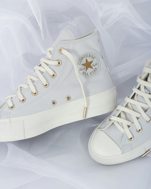 Pair of white leather sneakers on a plain background